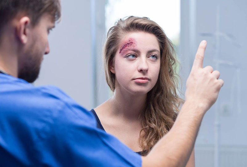 A lady with Head injury in Lindsay, ON Woman with head injury being examined by medical professional in Lindsay, ON, Canada