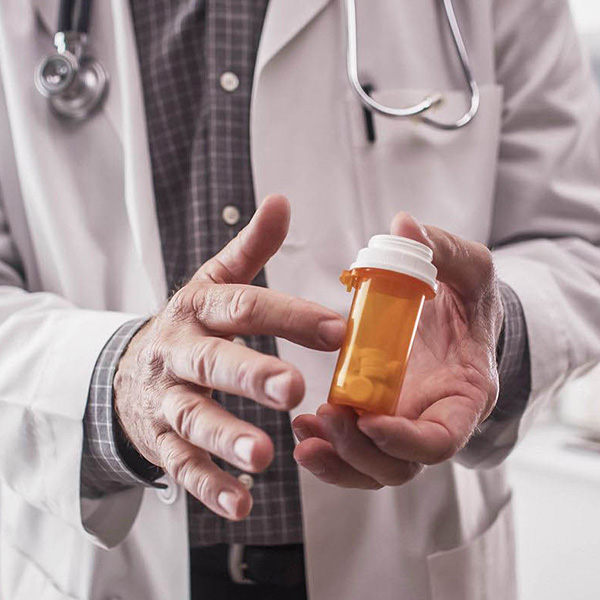 Doctor holding pill bottle with pills in Oshawa, Ontario