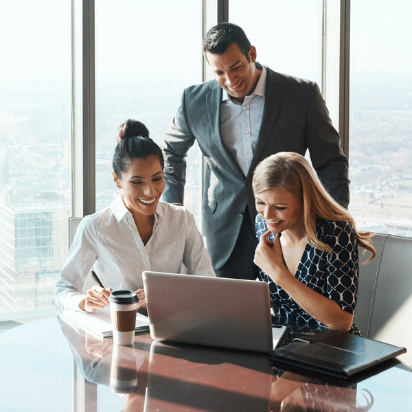 three business professionals huddled over a laptop